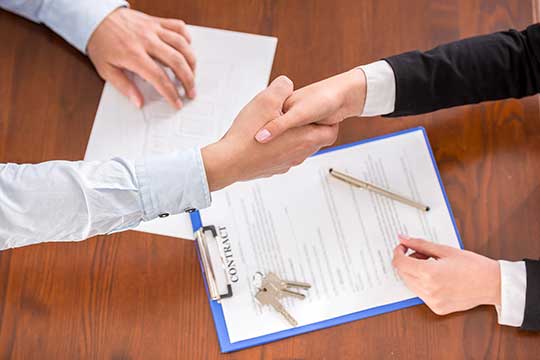 a landlord and tenant shake hands after signing a lease agreement