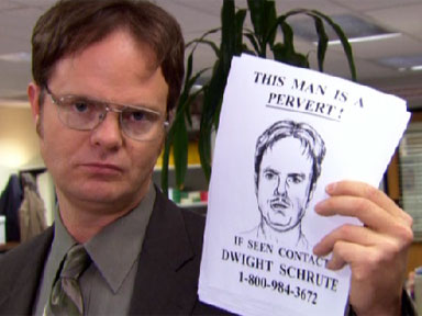Dwight Shrute from The Office holding a sign that has defamed his likeness