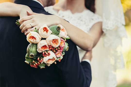 marriage between bride and groom holding flowers