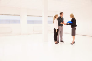 landlord shaking hands with tenants in empty apartment