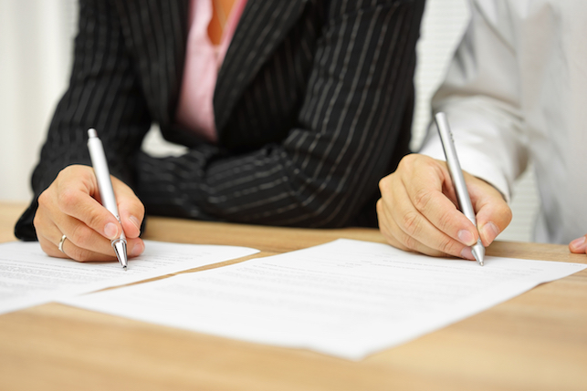 Businesswoman and businessman signing an Arbitration Agreement