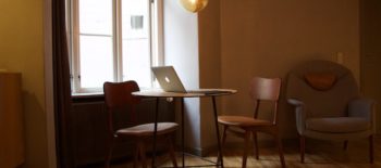 wooden chairs and table with a laptop next to a large window
