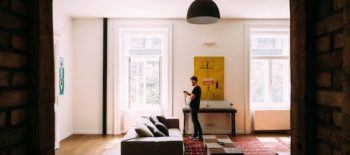 man standing in the living room of his new apartment after successfully answering the question how much should i spend on rent
