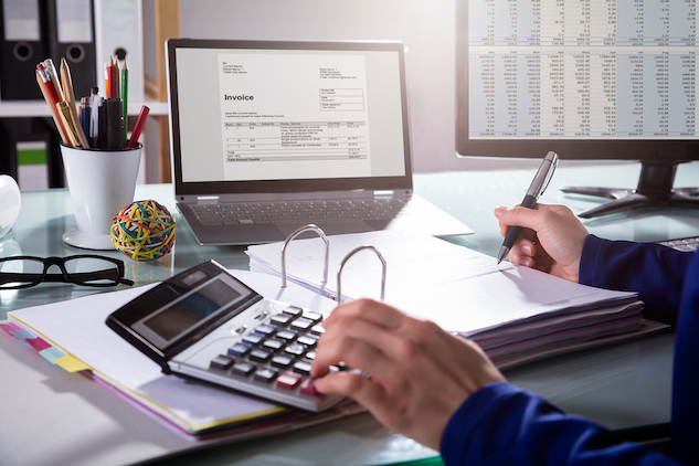 man with a calculator using an invoice to pay clients