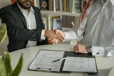 Two people shaking hands after signing documents