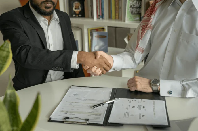 Two people shaking hands after signing documents
