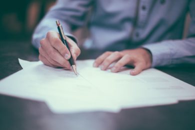 Person writing on a contract