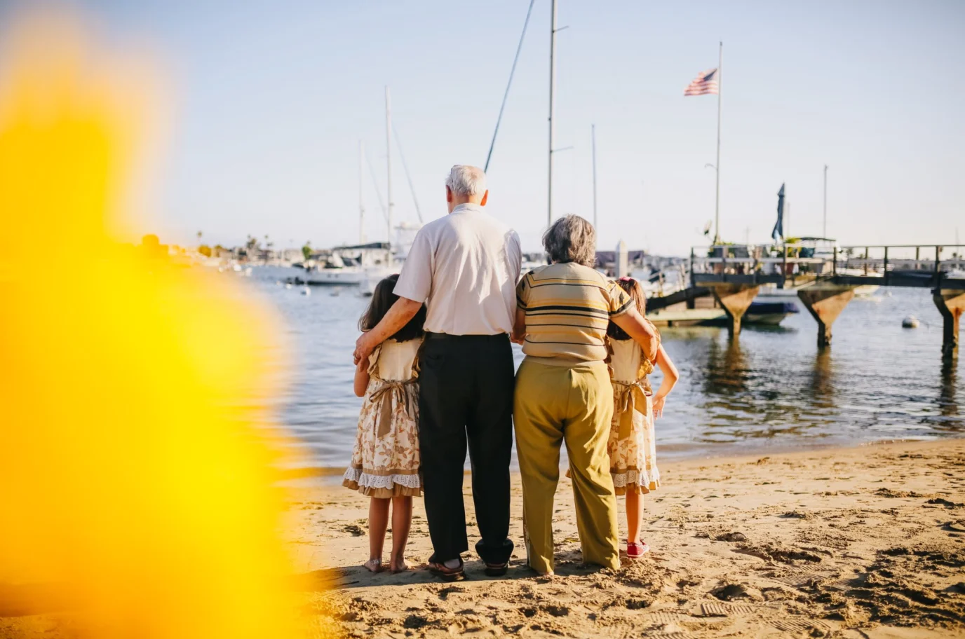 A family stood on a beach looking out to sea at boats