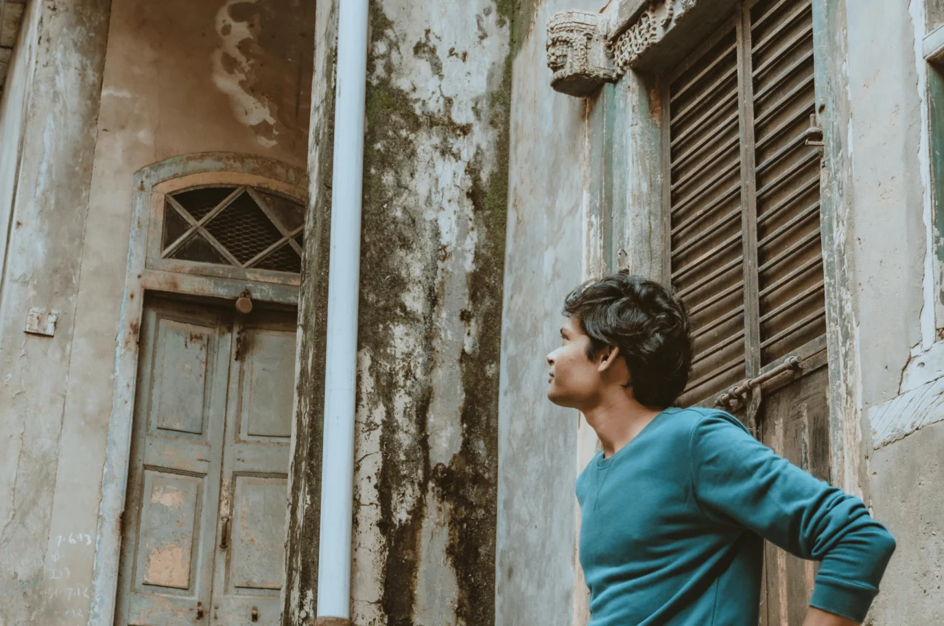 young man in front of a dilapidated building